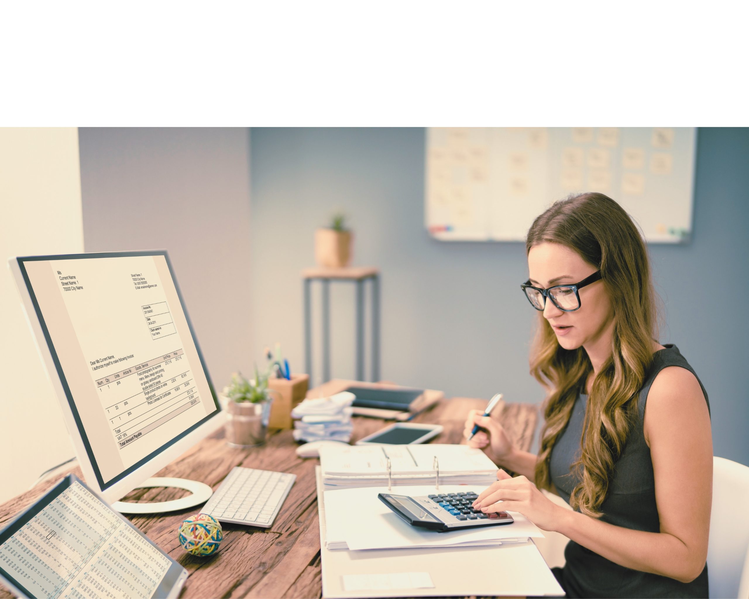 Femme travaillant sur un bureau avec une calculatrice et des documents financiers, face à un écran affichant une facture.@AndreyPopov_Getty